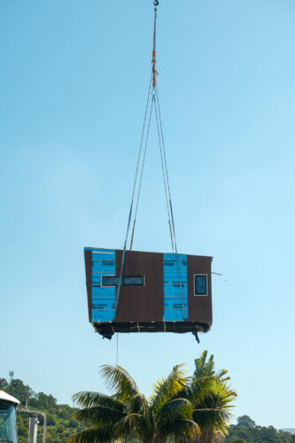 Crane lifting a module onto a modular home on a sloping block in Cringila NSW