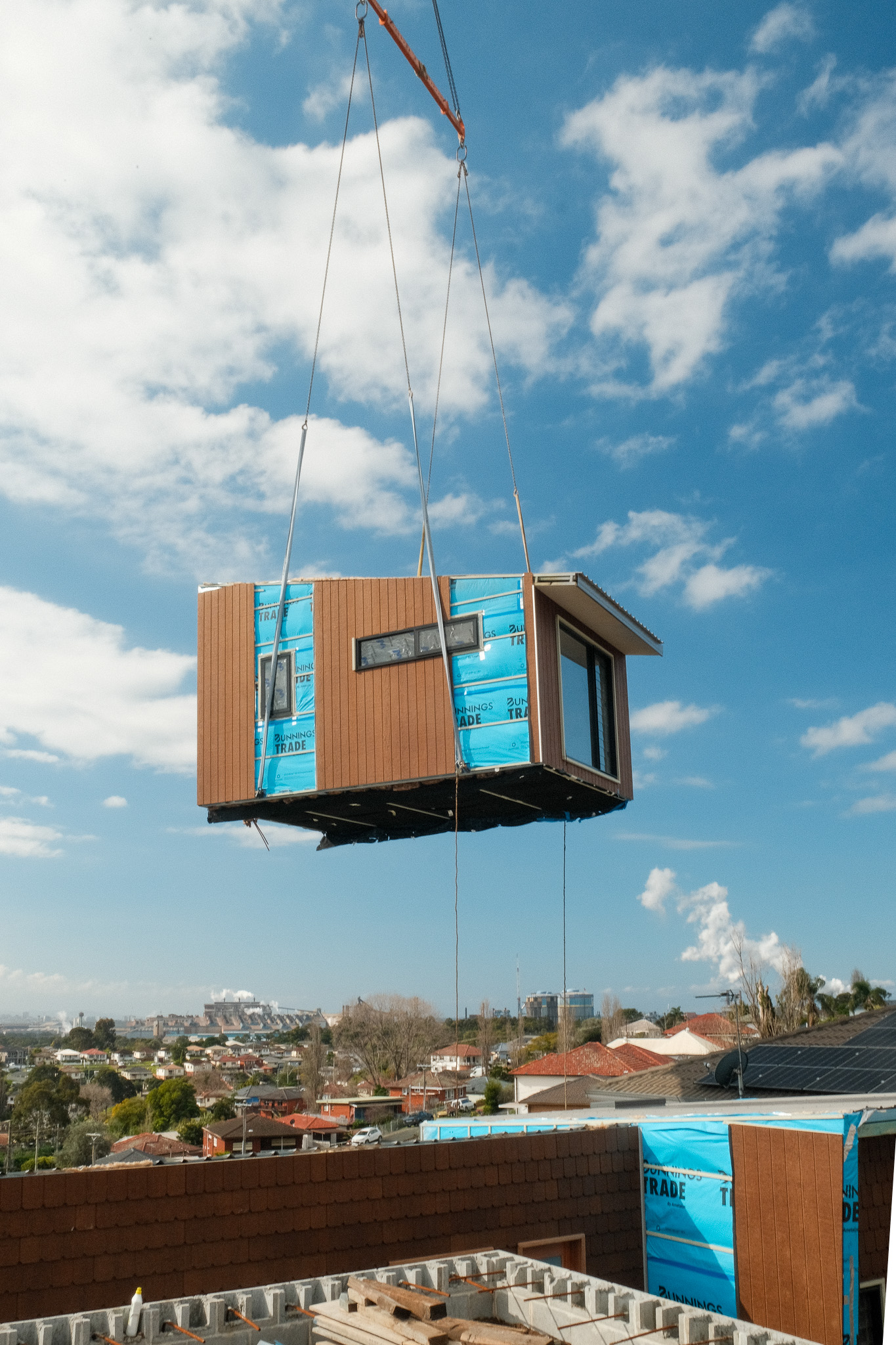 Crane lifting a module onto a modular home on a sloping block in Cringila NSW